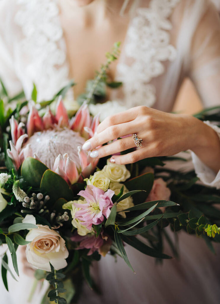 白いウェディングドレスの花嫁は美しいウェディングブーケをストロークします。半像 - 写真・画像