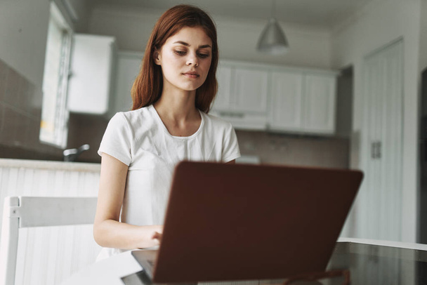 woman with laptop sitting at table freelancer working outside office kitchen interior - Photo, Image
