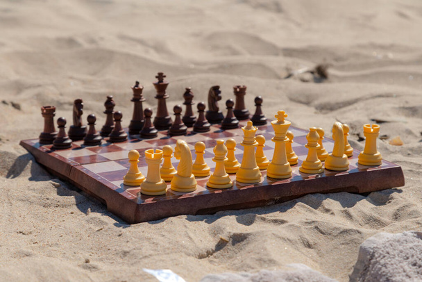 Les échecs jouent sur le plateau à la plage. Chessboard sur le sable par une journée ensoleillée. - Photo, image
