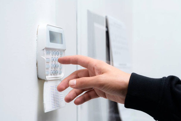 Hand entering alarm system password of an apartment, home or business office. Surveillance and protection console against rubbery and thief - 写真・画像