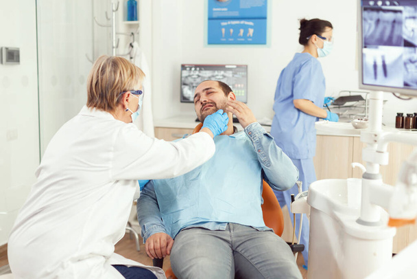 Стоматолог перевіряє, чи пацієнт відчуває біль під час прийому стоматології. - Фото, зображення