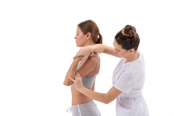 Medico fisioterapista che allunga una giovane donna sportiva isolata su sfondo bianco - Foto, immagini