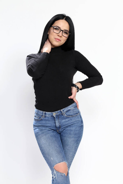 Atraktivní evropská dívka s černými vlasy a brýlemi pózující ve studiu na izolovaném pozadí. Styl, trendy, módní koncept. - Fotografie, Obrázek