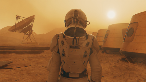 Astronaut auf dem Planeten Mars, macht einen Umweg um seine Basis. Astronaut auf dem Weg entlang der Basis. Kleiner Staubsturm. Die Satellitenschüssel sendet Daten an den Boden. 3D-Illustration - Foto, Bild