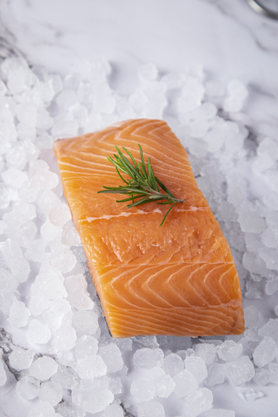 salmon with a sprig of rosemary on ice on a white marble background - Fotografie, Obrázek