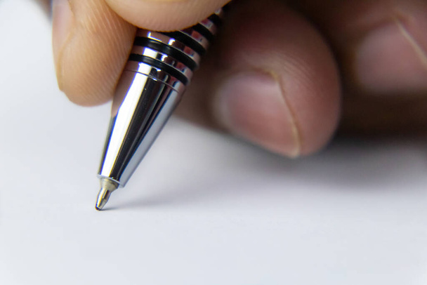 Close-up shot van een pen nib schrijven op papier met een menselijke hand schot in macro-modus - Foto, afbeelding