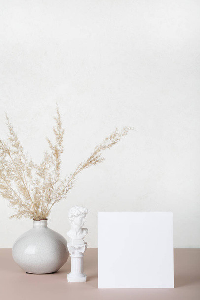 Üres papír kártya, meghívó mockups kis szobor és pampa fű vázában fehér és bézs háttérrel. Modern lakberendezési koncepció. másolás helye - Fotó, kép