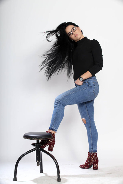 Attractive european girl with black hair and glasses posing in studio on isolated background. Style, trends, fashion concept. - Foto, Imagen