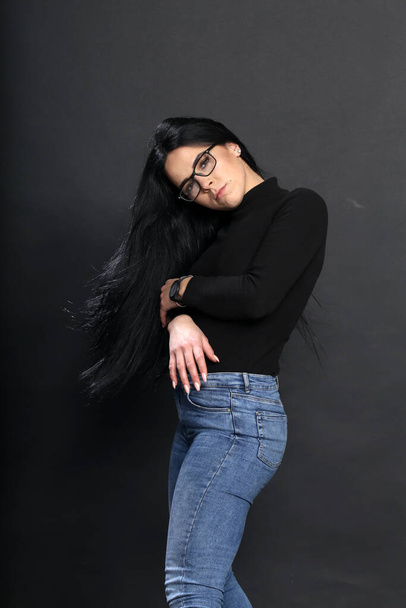 Привлекательная европейская девушка с черными волосами и очками позирует в студии на изолированном фоне. Стиль, тенденции, концепция моды. - Фото, изображение