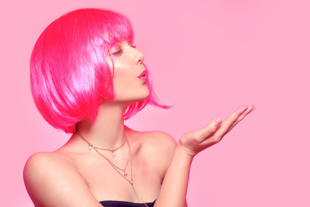 Κορίτσι με ροζ μαλλιά, καστανά μαλλιά. Το μοντέλο στέλνει ένα φιλί, ένα μέρος για ένα προϊόν, για κείμενο - Φωτογραφία, εικόνα