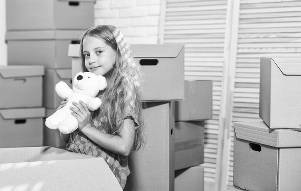 Excited about new house. Girl child play with toy near boxes. Move out concept. Prepare for moving. Moving out. Packaging things. Rent house. Family house. Delivering service. Apartment for family - Фото, изображение