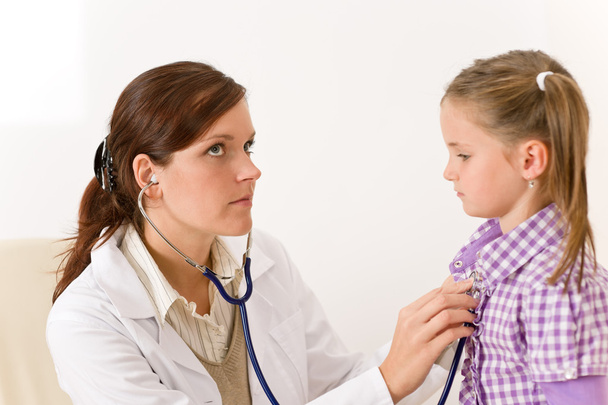 Female doctor examining child with stethoscope at clinic - Foto, afbeelding