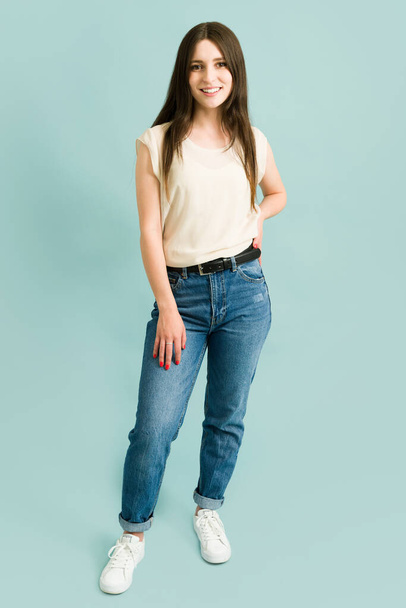 Studio shot of an attractive caucasian young woman posing in casual clothes and smiling against a blue background - Fotoğraf, Görsel