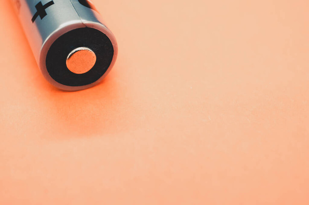 A closeup shot of a battery on a light orange background - Foto, Imagen