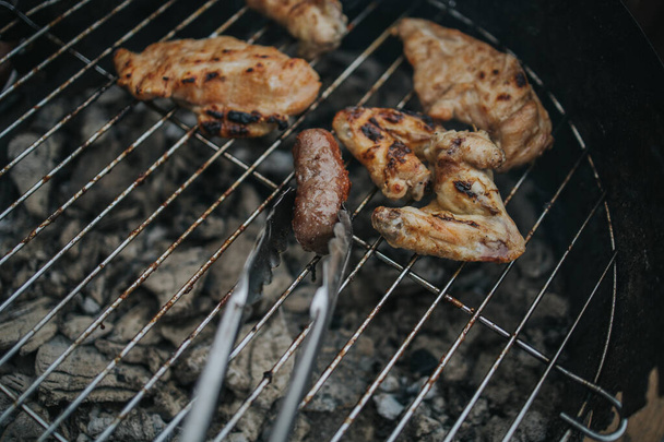 A closeup shot of sausages and meat preparing in the grill - Foto, imagen