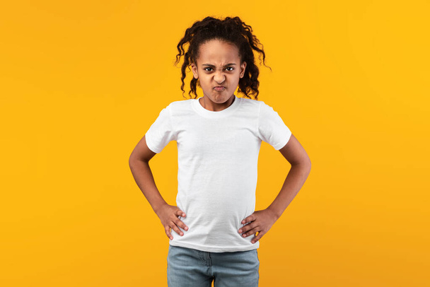 Vihainen nuori musta tyttö seisoo kädet lantiolla - Valokuva, kuva