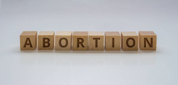 Una pancarta con bloques de madera con el texto: "Aborto" sobre un fondo claro - Foto, imagen