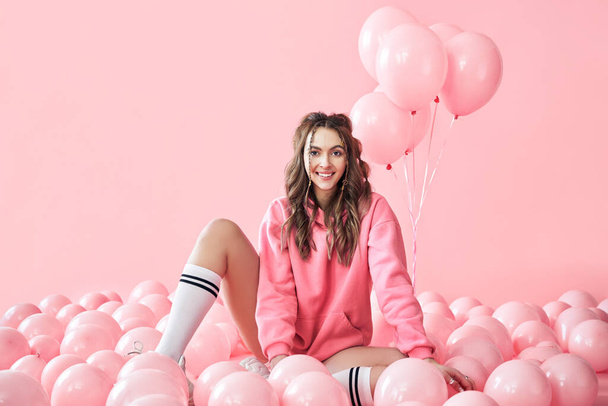 Junge trendige Frau posiert mit rosa Luftballons auf rosa Hintergrund - Foto, Bild