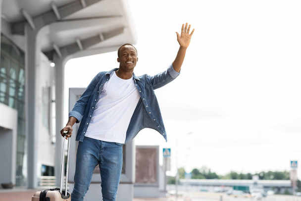 Portrait d'un beau Noir heureux attrapant un taxi près du terminal de l'aéroport - Photo, image