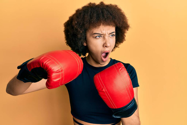 Young hispanic sporty girl using boxing gloves angry and mad screaming frustrated and furious, shouting with anger. rage and aggressive concept.  - Φωτογραφία, εικόνα