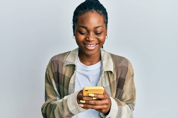 Jeune femme afro-américaine utilisant smartphone souriant et riant fort à haute voix parce que drôle blague folle.  - Photo, image