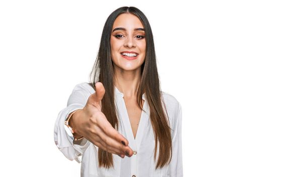 Young beautiful woman wearing casual white shirt smiling friendly offering handshake as greeting and welcoming. successful business.  - Foto, Imagem