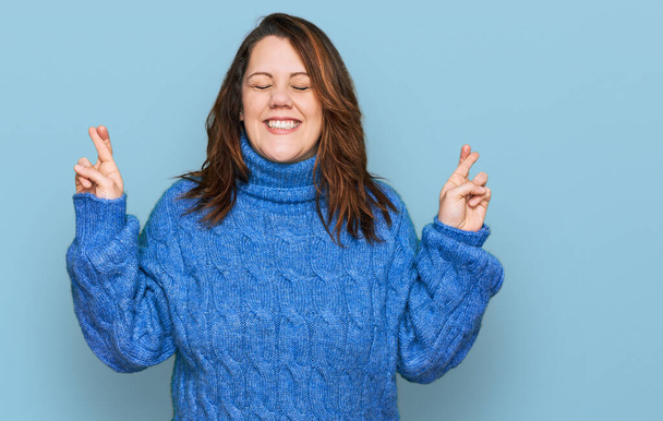 Young plus size woman wearing casual clothes gesturing finger crossed smiling with hope and eyes closed. luck and superstitious concept.  - Fotoğraf, Görsel