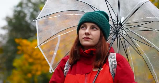 Aranyos nő, aki élvezi az esős időt. Esernyő alatt áll és nyújtózkodó kézzel fogja a vízcseppeket. - Felvétel, videó