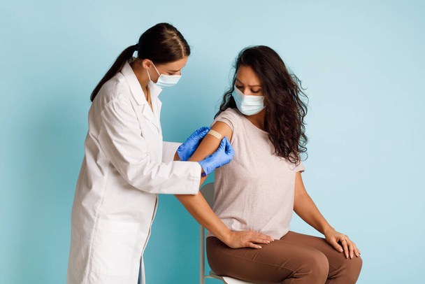 Médecin généraliste Vacciner une jeune patiente sur fond bleu - Photo, image