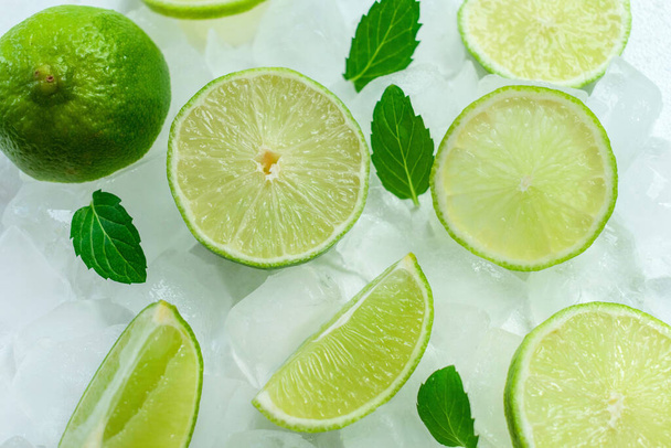 Lime slices and mint leaves on ice. View from above. - Fotografie, Obrázek