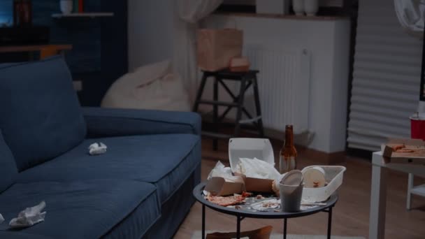 Großaufnahme des Tisches mit Essensresten darauf in einem leeren, ungeordneten, chaotischen Wohnzimmer - Filmmaterial, Video