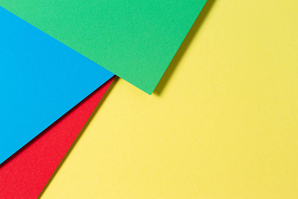 Soyut renk kağıtları geometri düz kompozisyon arkaplan mavi, sarı, kırmızı ve yeşil renk tonlarıyla - Fotoğraf, Görsel