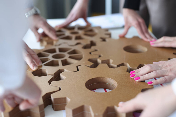 Employees connect together wooden gears on work table - Fotografie, Obrázek