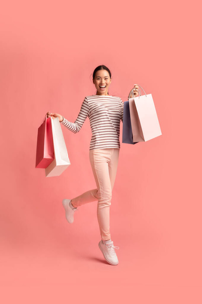 Isoja kauppoja. Täysi pituus nuori aasialainen nainen käynnissä kanssa ostoskassit - Valokuva, kuva