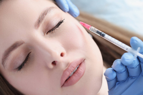 A nőnek fiatalító injekciót adnak be hialuronsavval az arcába. - Fotó, kép