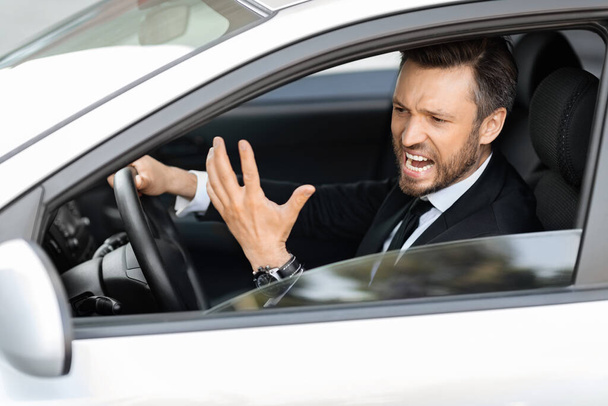 Expresivo hombre de negocios de mediana edad gritando mientras conduce el coche - Foto, Imagen