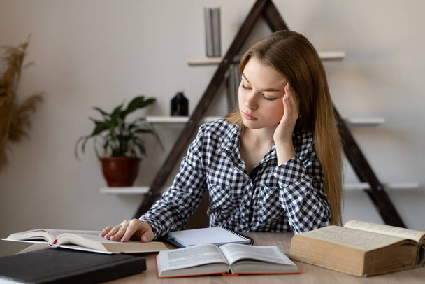 Stress headache and fatigue problem of female freelance teacher or student at workplace. Open books on the desk. Remote work online. - Φωτογραφία, εικόνα