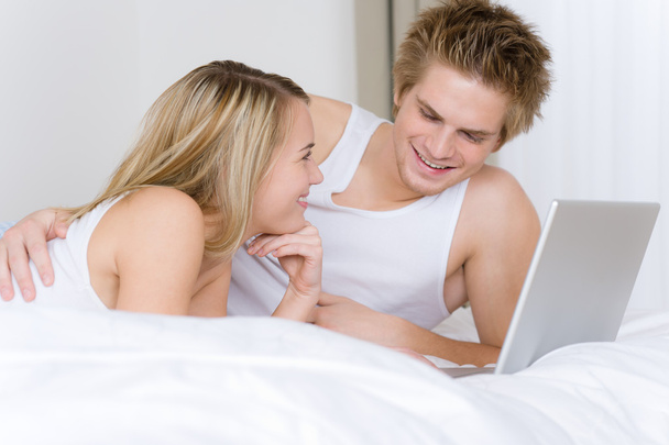 Young couple relax in bed with laptop lying down together - Photo, Image