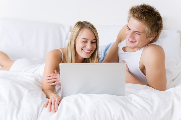 Young couple relax in bed with laptop lying down - Фото, зображення