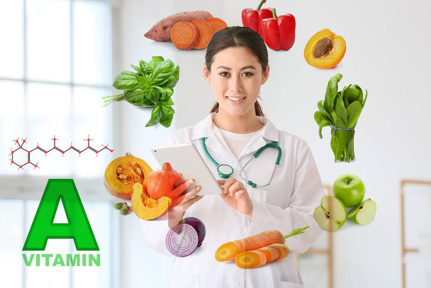 Lékař s počítačem tablet a zdravé produkty bohaté na vitamin A na virtuální obrazovce na klinice - Fotografie, Obrázek