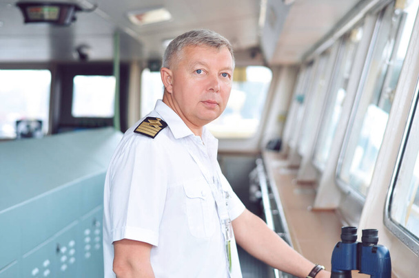 Beyaz gömlekli bir kargo gemisinin kaptanı kaptanın köprüsünden emir alır.. - Fotoğraf, Görsel