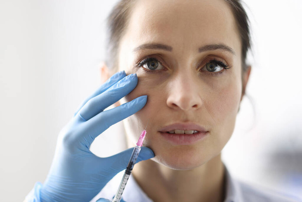 医者は女性に鼻骨の折り目への注射を与える. - 写真・画像