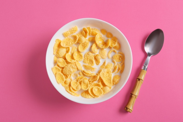 Bowl with tasty cornflakes on color background - Foto, imagen