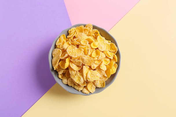 Schaal met lekkere cornflakes op kleur achtergrond - Foto, afbeelding