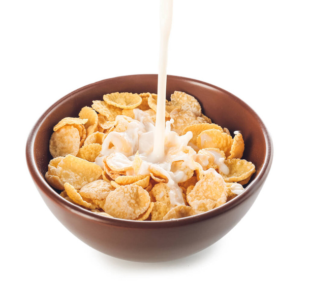 Pouring of milk into bowl with cornflakes on white background - Photo, Image