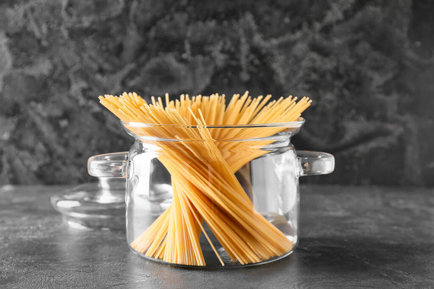 Stylish cooking pot with uncooked pasta on dark background - Foto, Imagen