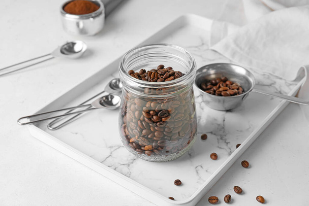 Tarro y olla con granos de café sobre fondo claro - Foto, Imagen