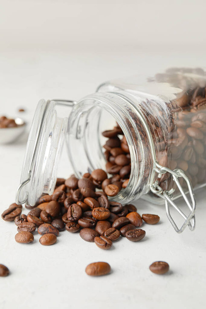 Jar with coffee beans on light background - Φωτογραφία, εικόνα
