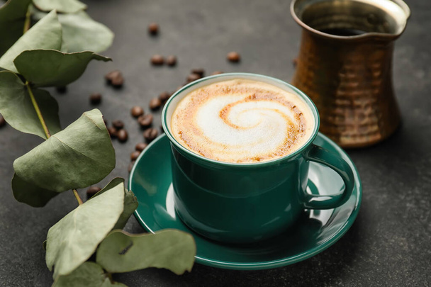 Filiżanka gorącego cappuccino i dzbanek do kawy na ciemnym tle - Zdjęcie, obraz