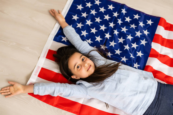 Cute little girl and USA flag on background - Фото, изображение